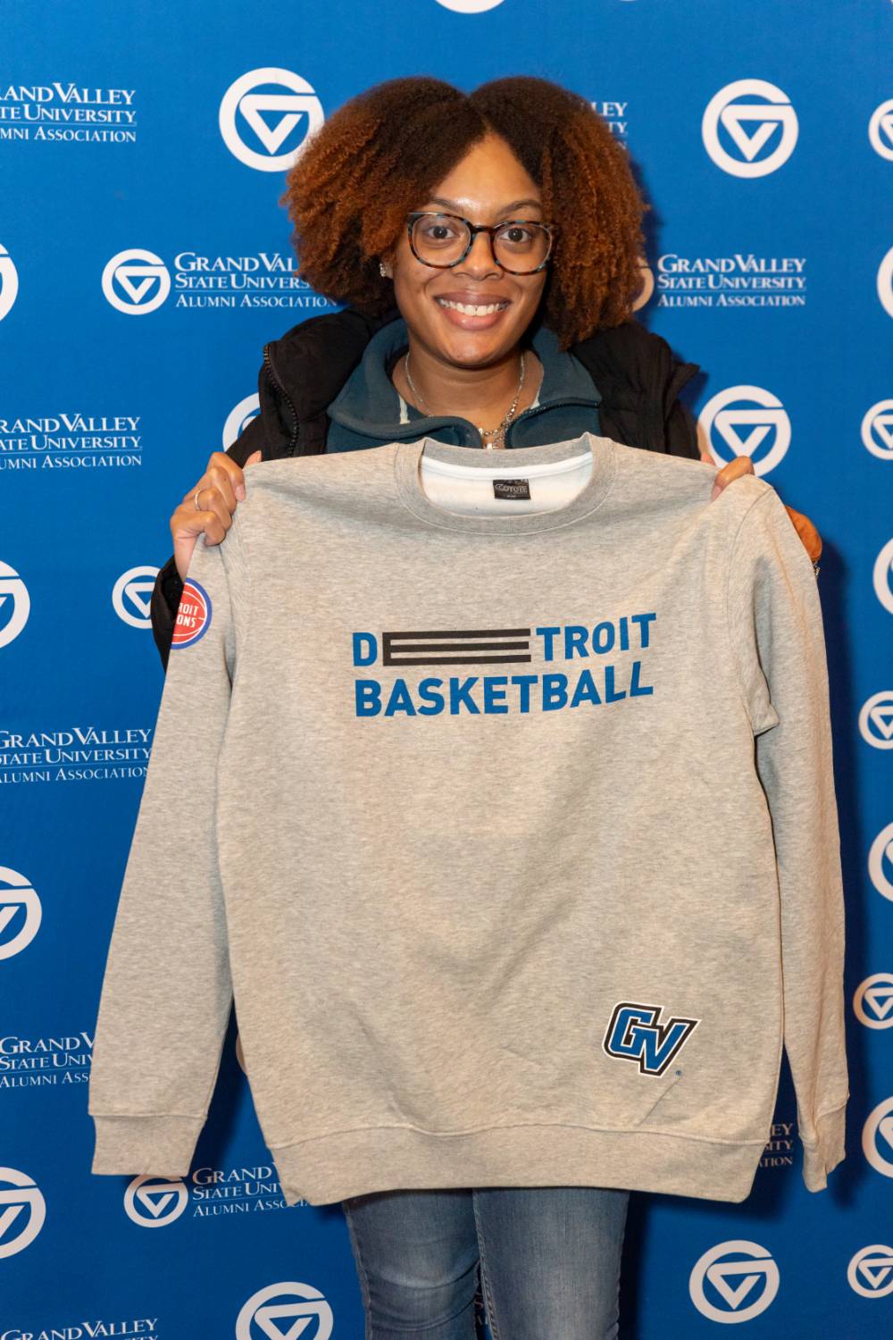 An alum and her shirt in front of the GVSU Alumni Relations backdrop.